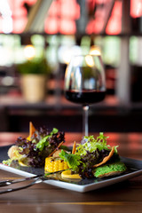 Side view of gourmet healthy snack with mixed greens, nachos, roasted chicken breast and grilled corn on blurred background