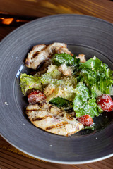 Classic caesar salad with grilled chicken fillet, greens and cherry tomatoes in daylight