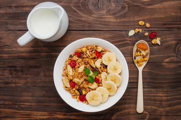Chocolate granola in the bowl on rustic wooden background with milk
