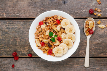 Granola with banana and berGranola with banana and berries on wooden background