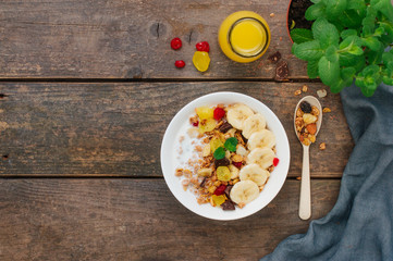Granola with banana and berries in the bowl on rustic wooden background with copyspace
