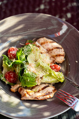 Classic caesar salad with grilled chicken fillet, greens and cherry tomatoes in daylight