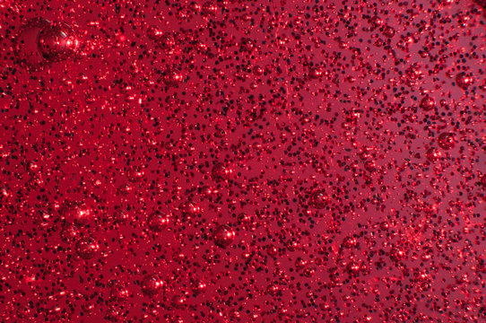 Macro of red slime with glittering multicolor particles and bubbles