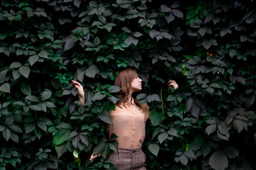 young girl stands in green leaves alone with nature, a woman touches plants and dreams, a concept of a man in nature