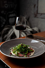 Tenderloin roast beef with creamy dairy sauce, fresh arugula and chili pepper on a restaurant blurred background