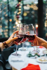 Fototapeten hands clinking glasses of christmas. Celebration. Hands holding the glasses wine making a toast. © develi