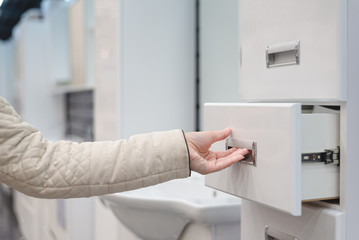 Woman open empty bath furniture drawer. Customer is choosing a new bath set furniture.