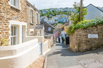 Old stone cottages on narrow street in beautiful Cornish harbour town Polruan, South Cornwall, UK