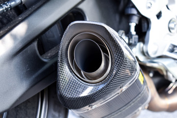 Close up view of a black carbon motorcycle exhaust pipe
