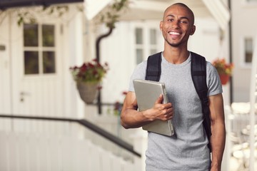 Smiling African Student man with laptop, mall background, bokeh