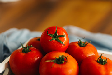 Fresh, pink and red tomatoes on white, different backgrounds and in a wooden crate