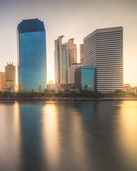 Naklejka premium Lake in Public Park under Skyscrapers at Sunrise. Benjakiti Park in Bangkok, Thailand