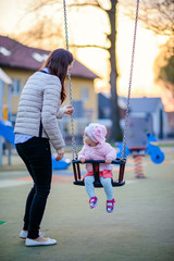 Mother and little daughter are walking and playing on the playground in the park