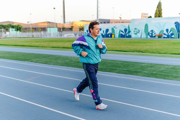 Man on running track prepared to run, wearing vintage sportswear
