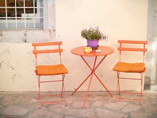 Fototapeta na wymiar Orange chairs and table on the street