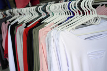 T-shirts on hangers, a large selection. Different design. Shopping template background.