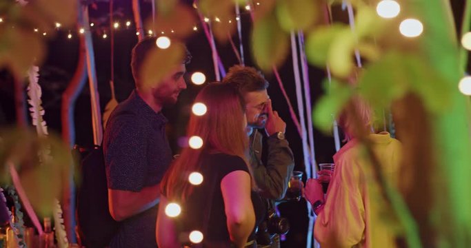 Group of cheerful millennial friends socializing on camp party staying in amazing holiday interior outdoors. Night hangout.