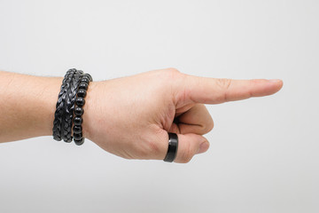 Pointing hand. Hand of a white man wearing black accessories, pointing with the index finger. Side view, white background.
