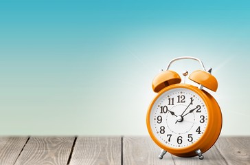 Orange retro alarm clock on wooden table on wall background