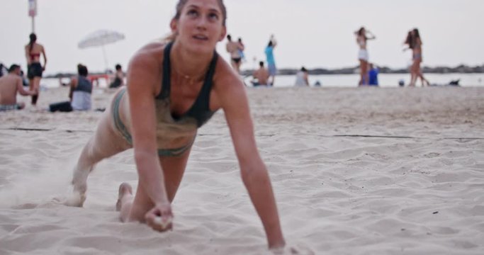 Female Beach Volleyball player diving on the sand during a game