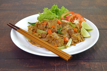 Vegetarian food : Stir fried flat noodle with black soy sauce, tofu, carrots and green vegetables. Vegetarian food for vegetarian festival. Thai style stir fry flat noodle. 