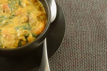 Shrimp and squash chowder with spinach and potatoes in bowl