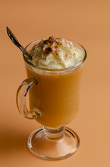 pumpkin latte with whipped cream in a glass jar on a colored background