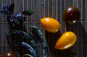 Autumn still life - asparagus beans, purple Basil, yellow and chocolate tomatoes on bamboo Mat