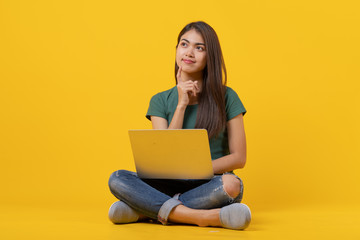 beauty asian teenager in green tee shirt thinking / imagination / question isolated on yellow background in studio.