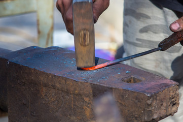 blacksmith performs the forging of hot glowing metal on the anvil
