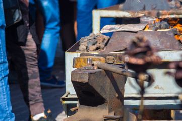 blacksmith performs the forging of hot glowing metal on the anvil