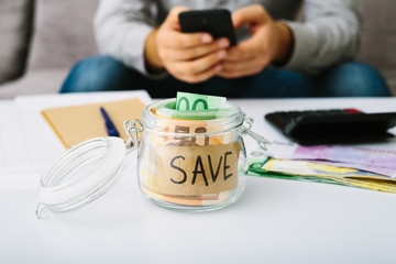 Euro bills banknote in a glass bottle for saving. Man doing his accounting. Small business: deposit and lending, interest rate reduction.