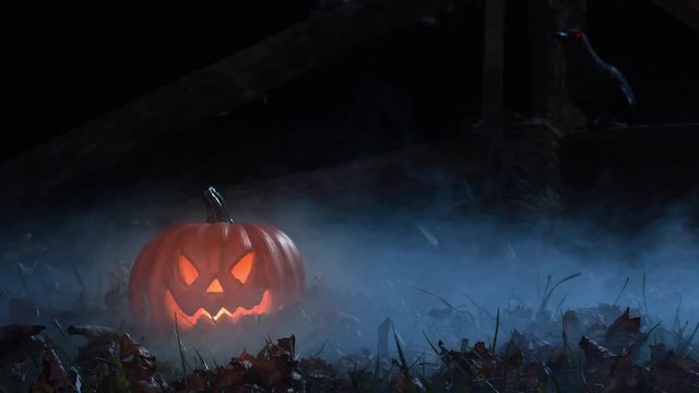 A glowing scary Jack O&rsquo;Lantern sitting in the grass with a red eyed raven in the background as a fog rolls through at night