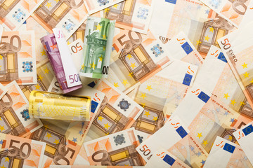 Rolls of euro banknotes on scattered euro money. Business, finance, saving, banking concept, exchange rates. Frame, copy space, top view. - obrazy, fototapety, plakaty