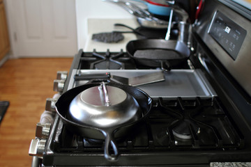Stainless steel melting dome in a cast iron skillet on the stove in a home kitchen.