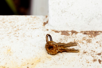 Old rusty keys forgotten on white concrete ledge.