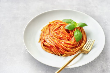 Pasta with tomato sauce and basil on white background