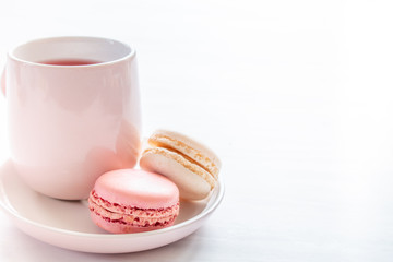 Fototapeta na wymiar Raspberry and Vanilla Macaroons, with Raspberry Tea in Pink Tea Cup, on White Table with Copy Space