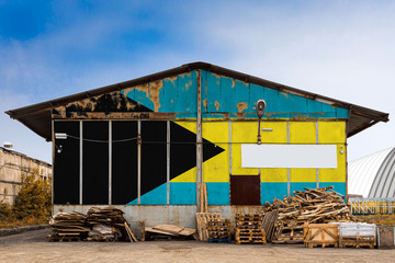 Close-up of the national flag of Bahamas. painted on the metal wall of a large warehouse the closed territory on a summer day. The concept of storage of goods, entry to a closed area, tourism