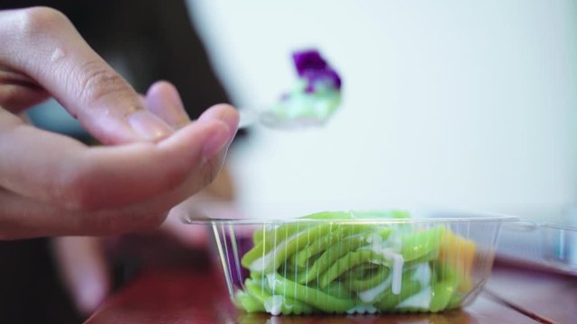 Eating Cendol, thai traditional dessert, with coconut milk in plastic container