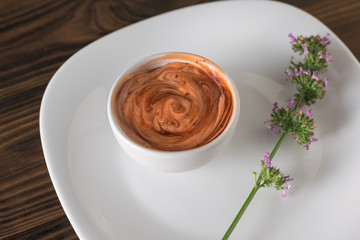 Sprig of herbs and sauce in a white bowl on a wooden table. Vegetarian sauce.