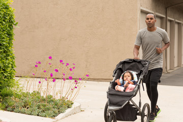 Father exercising and taking his daughter for a jog.