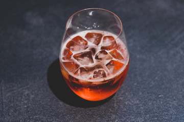 orange spritz cocktail glass with ice on dark concrete