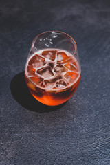 orange spritz cocktail glass with ice on dark concrete