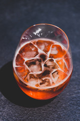 orange spritz cocktail glass with ice on dark concrete