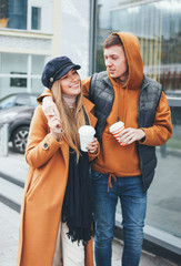 Happy young couple in love teenagers friends dressed in casual style walking together on city street in cold season