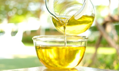 Pouring olive oil in the a glass bowl at stone kitchen and inside green garden view. Prepare for cooking concept. Healthcare and Beauty Concept.