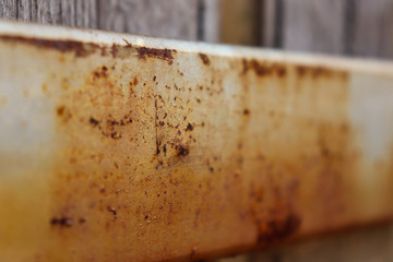rusty metal beam on back of wooden fence