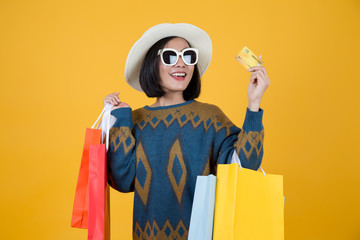 Women have paper bags, sunglasses and credit card. Surprised Shot in yellow studio background