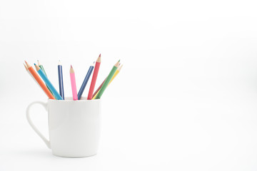Group of color pencils in a white cup on an isolated background.